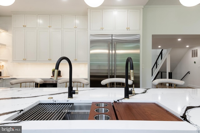 kitchen featuring stainless steel built in fridge, white cabinets, and sink