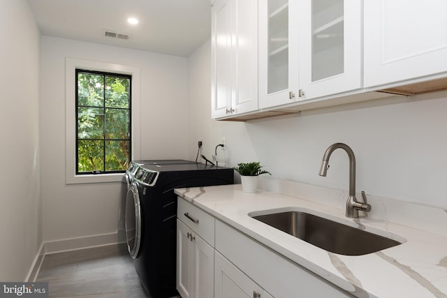 washroom featuring washing machine and clothes dryer, light wood-type flooring, cabinets, and sink