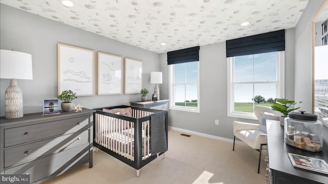 bedroom featuring a crib and light colored carpet