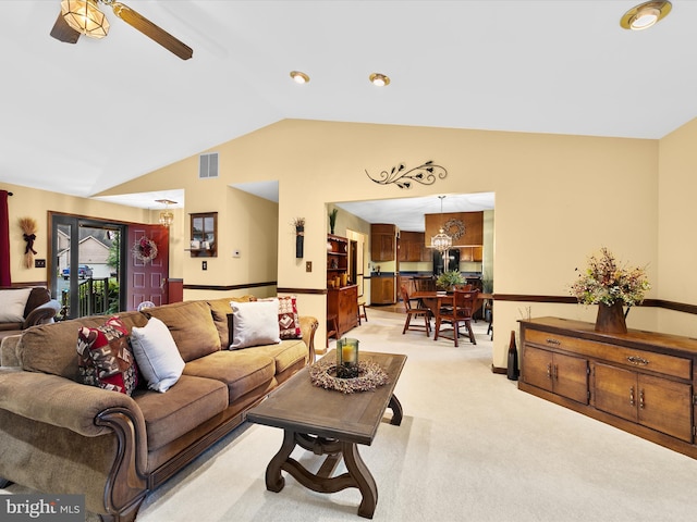 carpeted living room with ceiling fan with notable chandelier and lofted ceiling