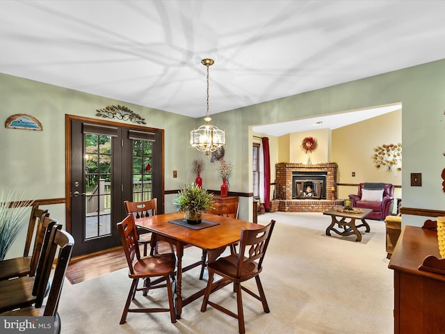 dining room with a brick fireplace, light colored carpet, and an inviting chandelier