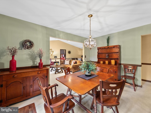 carpeted dining room featuring an inviting chandelier and vaulted ceiling