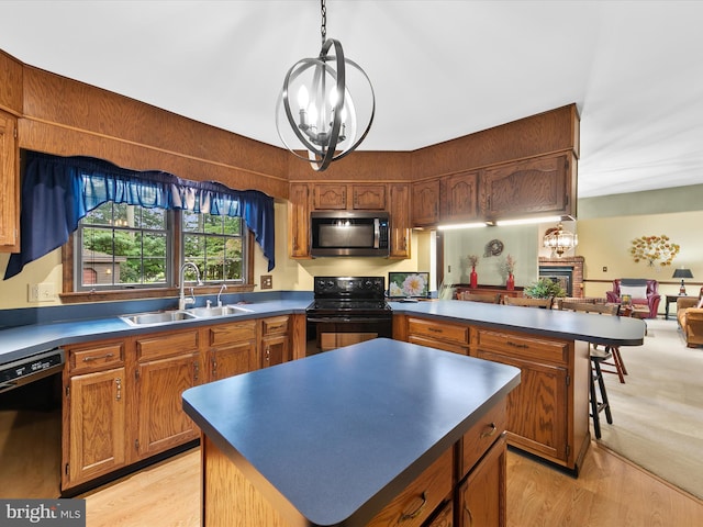 kitchen with sink, a kitchen island, light hardwood / wood-style flooring, an inviting chandelier, and black appliances