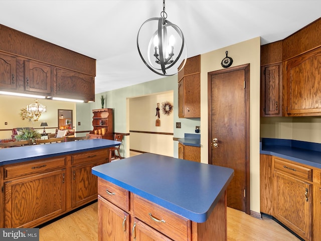 kitchen with an inviting chandelier, light hardwood / wood-style floors, a center island, and decorative light fixtures