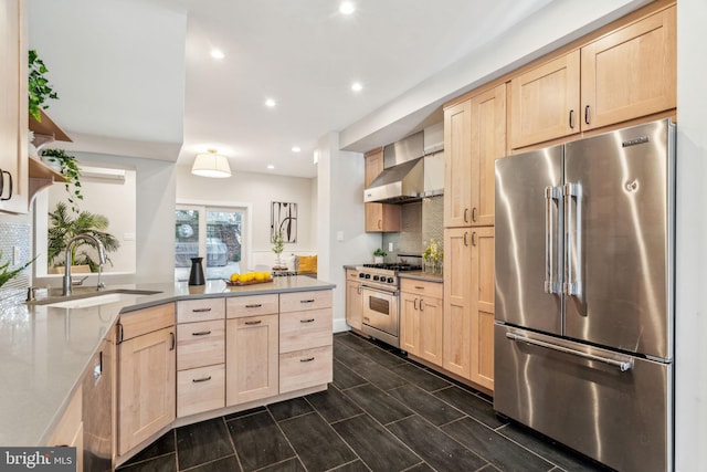 kitchen with light brown cabinets, high quality appliances, sink, and wall chimney range hood