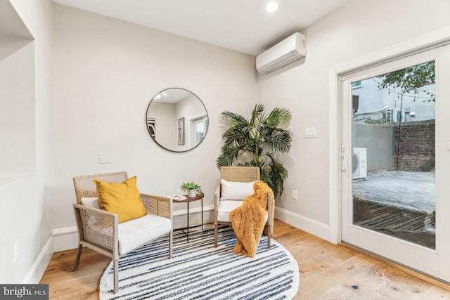 living area featuring a wall mounted air conditioner and light hardwood / wood-style floors