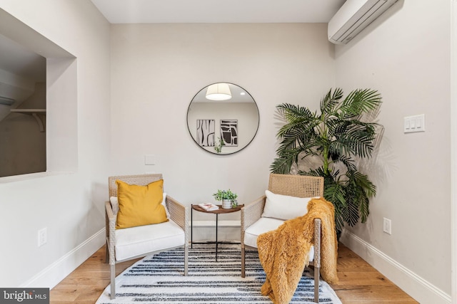 sitting room with hardwood / wood-style floors and a wall unit AC