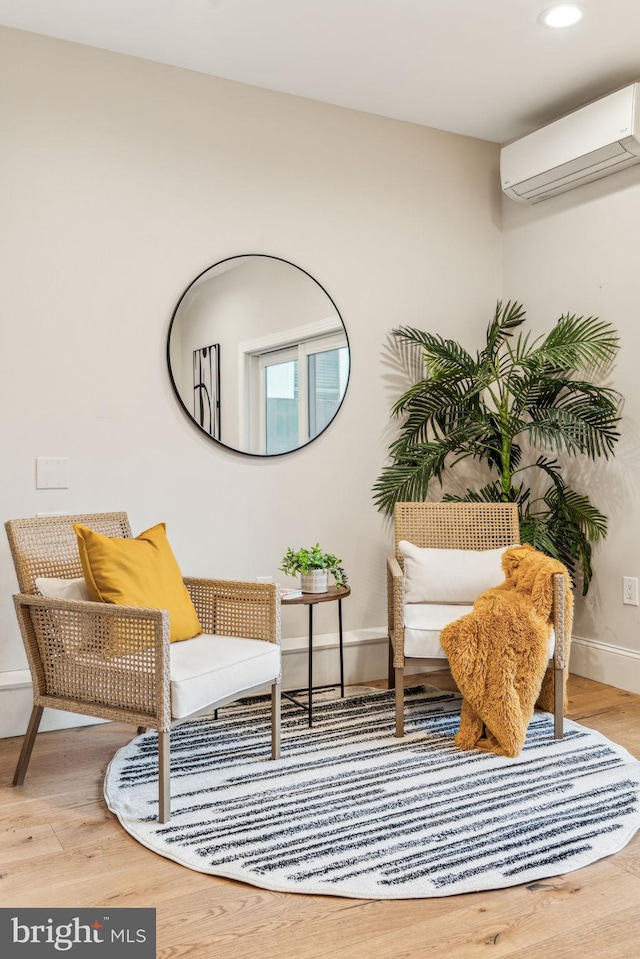 sitting room featuring light wood-type flooring and a wall unit AC