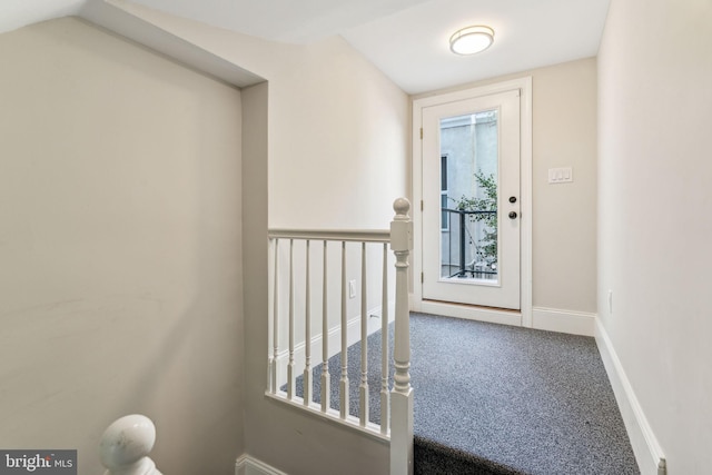 carpeted entrance foyer featuring vaulted ceiling