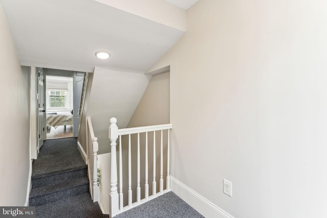 stairway featuring lofted ceiling and carpet