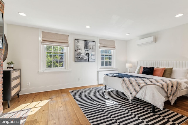 bedroom with hardwood / wood-style floors and an AC wall unit