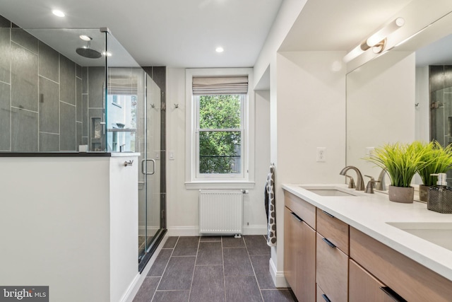 bathroom with radiator, vanity, and a shower with door