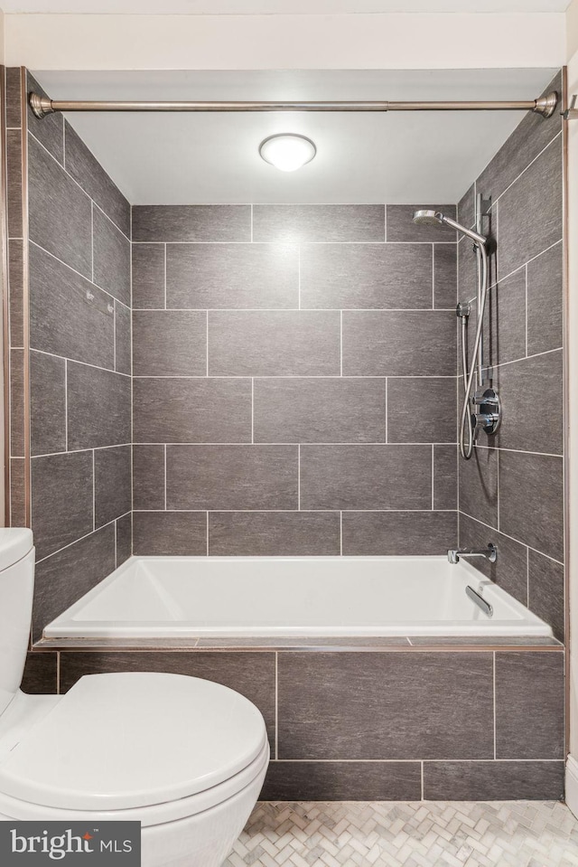 bathroom featuring toilet and tiled shower / bath combo