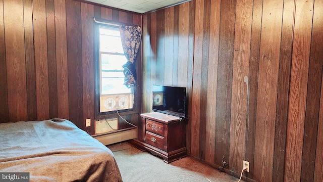 bedroom featuring wooden walls, light carpet, and a baseboard heating unit