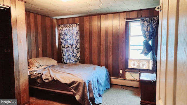 bedroom with a baseboard radiator, wood walls, and carpet