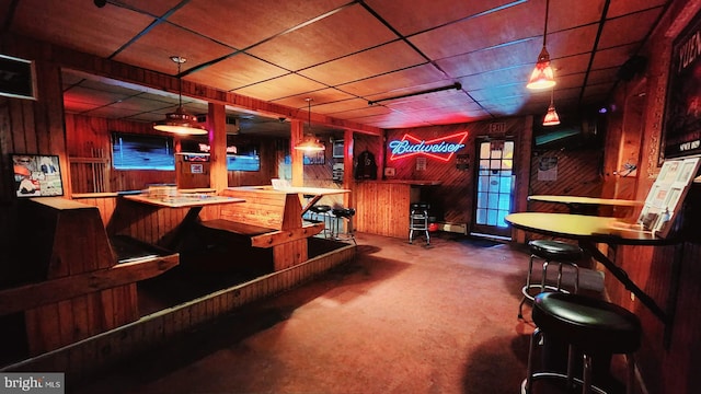 bar with carpet floors, wood walls, and decorative light fixtures