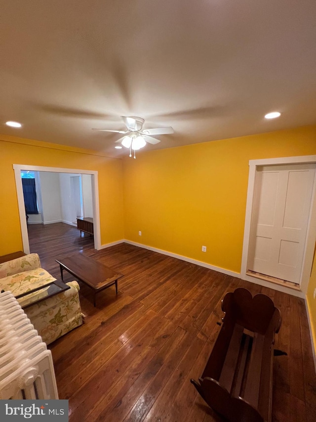 living room with dark wood-type flooring and ceiling fan