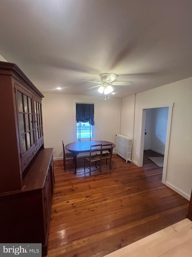 dining area featuring dark wood-type flooring, ceiling fan, and radiator