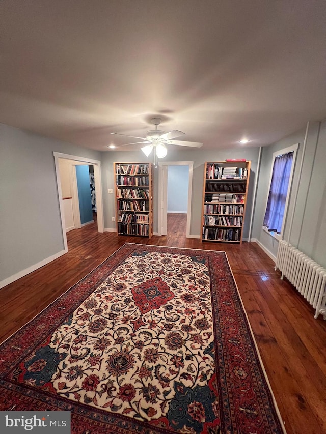 living room with wood-type flooring, radiator heating unit, and ceiling fan