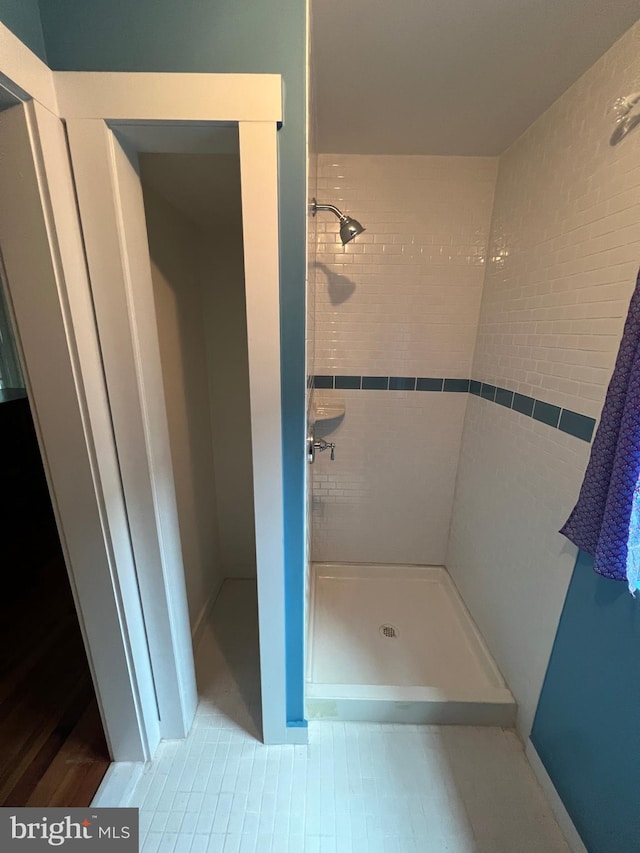 bathroom with a tile shower and tile patterned flooring