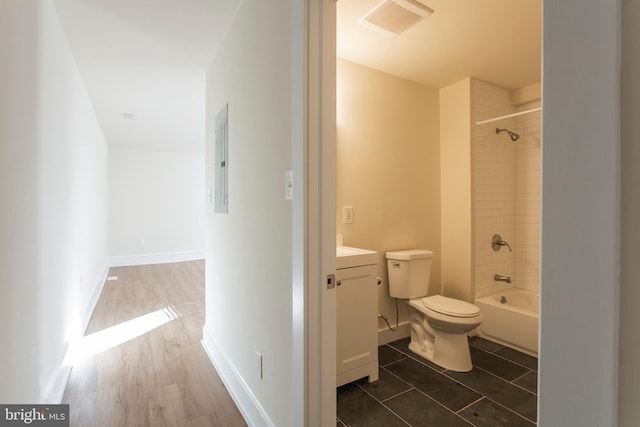 full bathroom featuring tiled shower / bath, vanity, electric panel, hardwood / wood-style flooring, and toilet