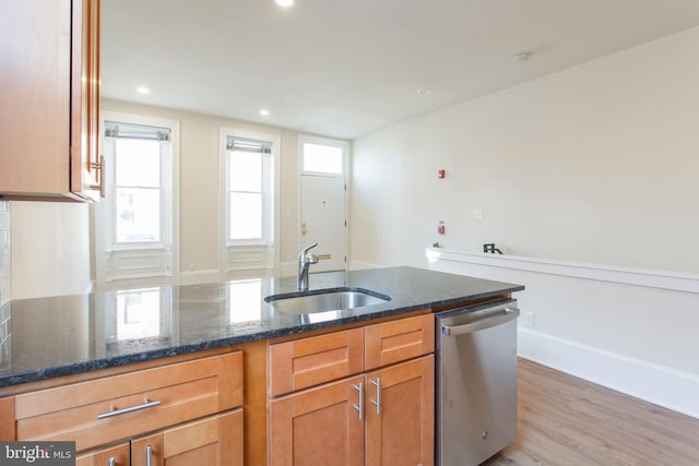 kitchen with dark stone countertops, dishwasher, light hardwood / wood-style floors, and sink