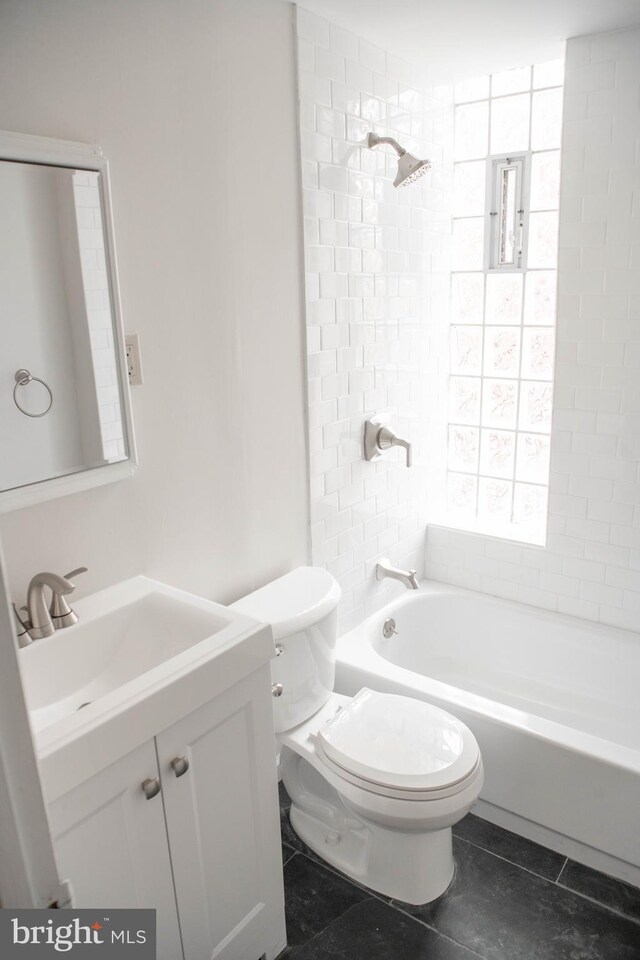 full bathroom with tile patterned flooring, tiled shower / bath combo, vanity, and toilet