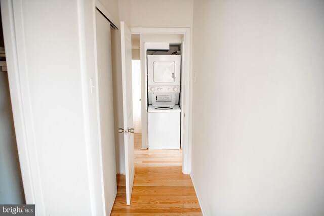 hallway with stacked washer / dryer and hardwood / wood-style floors