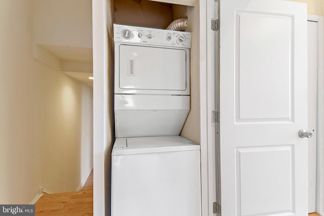 laundry room featuring wood-type flooring and stacked washing maching and dryer