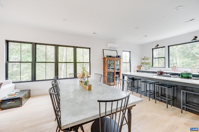 dining space with light wood-type flooring and a wall mounted AC