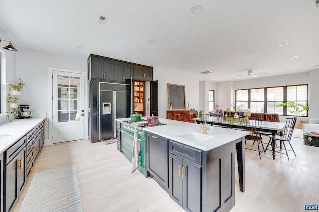 kitchen with light wood-type flooring, gas stove, sink, a kitchen island, and paneled built in refrigerator