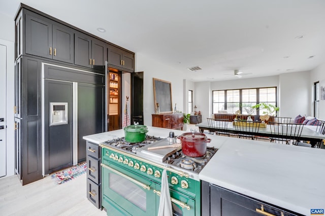 kitchen featuring dark brown cabinetry, premium appliances, light wood-type flooring, and ceiling fan