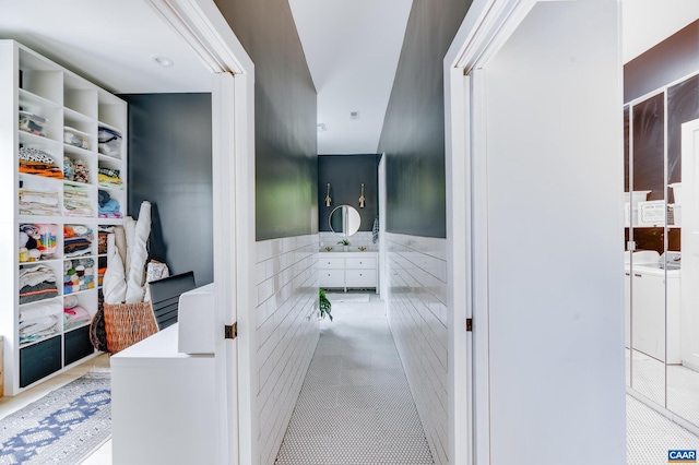 hall featuring tile walls, light tile patterned flooring, and sink