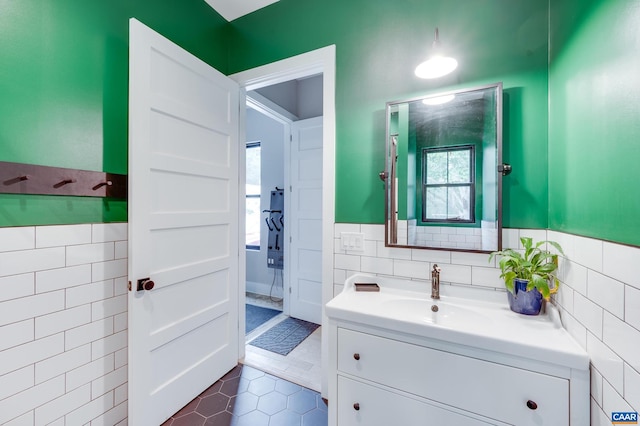 bathroom featuring a healthy amount of sunlight, tile patterned flooring, vanity, and tile walls