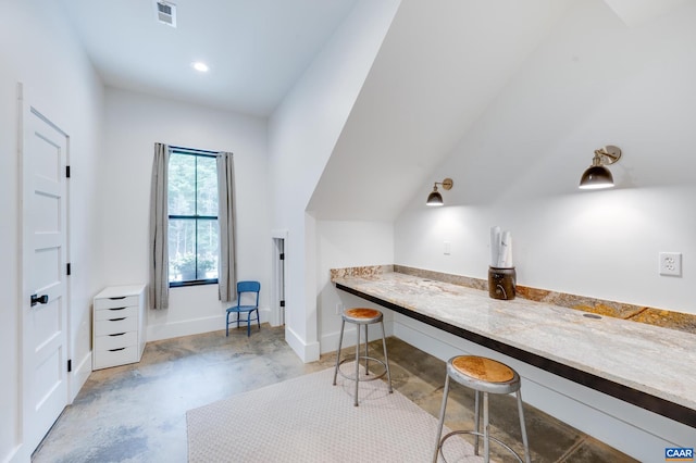 office area with built in desk and vaulted ceiling