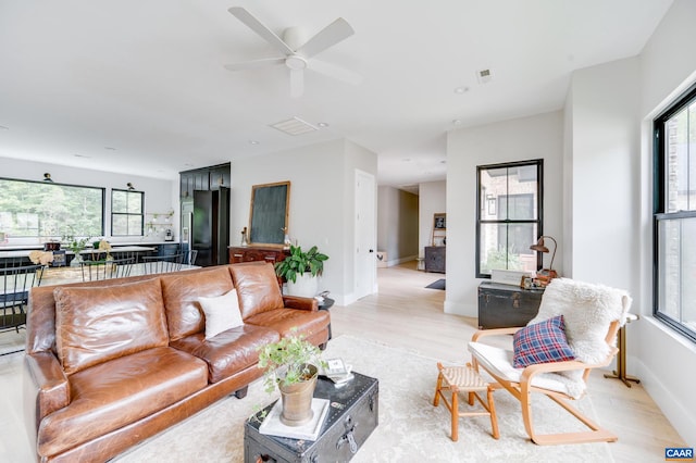 living room featuring ceiling fan, light hardwood / wood-style flooring, and a wealth of natural light