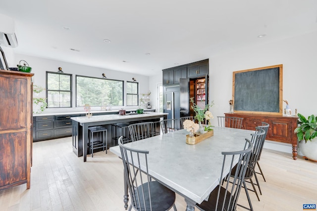 dining room featuring light hardwood / wood-style floors and a wall unit AC