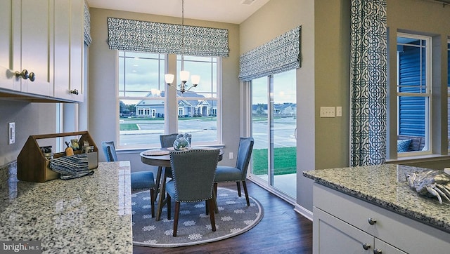 dining space with dark wood-type flooring and a notable chandelier