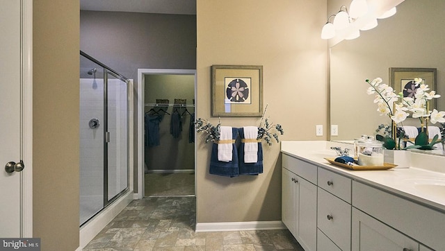 bathroom featuring a shower with door and vanity