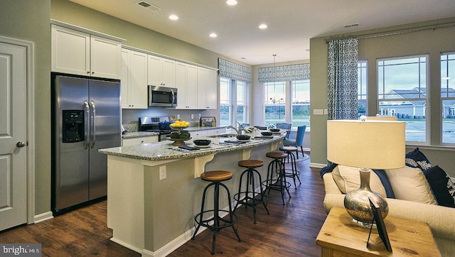 kitchen with a kitchen island with sink, appliances with stainless steel finishes, dark wood-type flooring, and white cabinetry