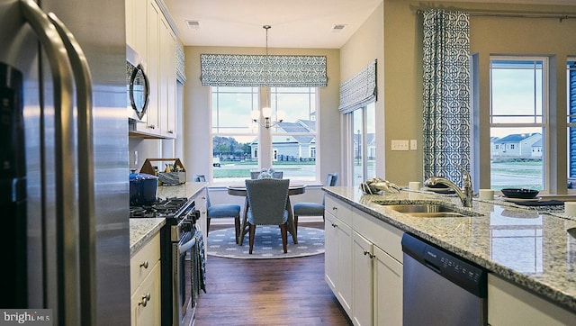 kitchen with white cabinets, sink, decorative light fixtures, appliances with stainless steel finishes, and dark hardwood / wood-style floors