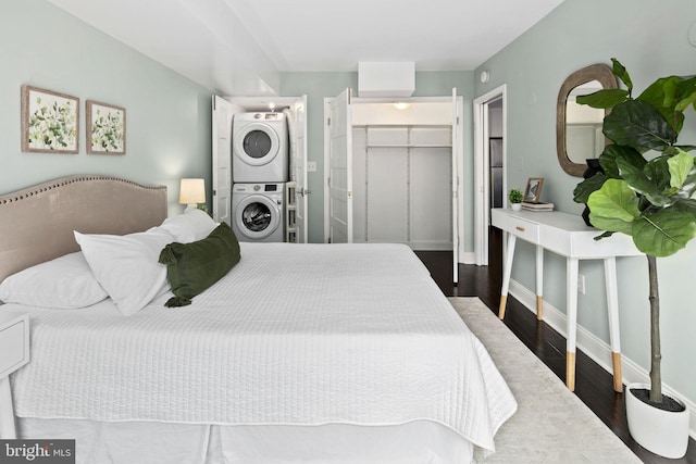 bedroom with stacked washer and dryer, dark wood-type flooring, a walk in closet, and a closet