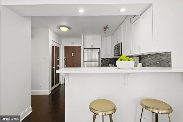 kitchen featuring appliances with stainless steel finishes, kitchen peninsula, white cabinetry, and a breakfast bar