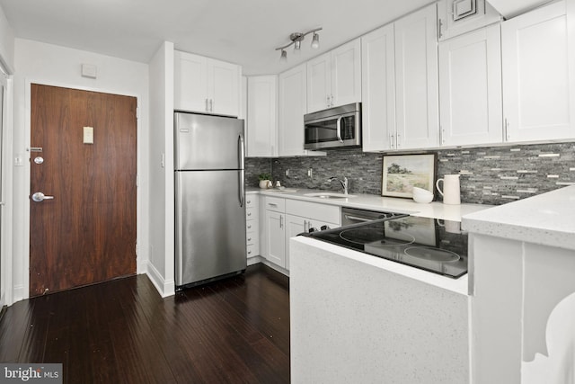 kitchen with white cabinets, sink, backsplash, appliances with stainless steel finishes, and dark hardwood / wood-style floors