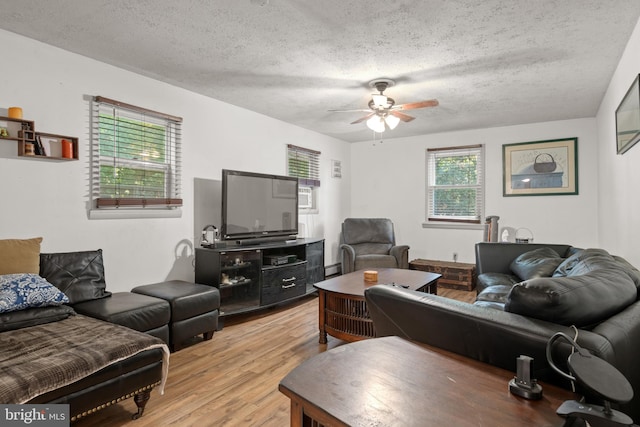 living room featuring ceiling fan, light hardwood / wood-style floors, and a textured ceiling