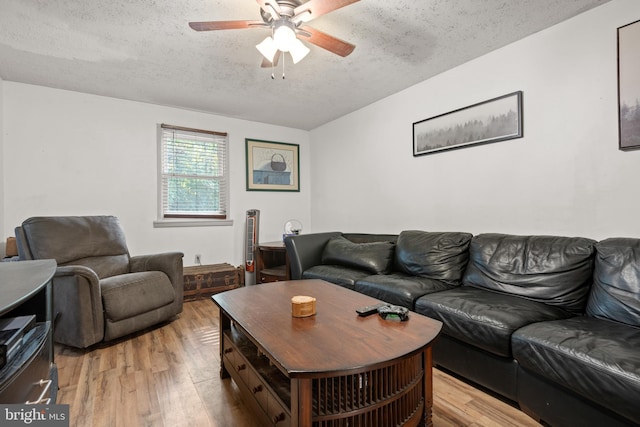 living room featuring ceiling fan, light hardwood / wood-style flooring, and a textured ceiling