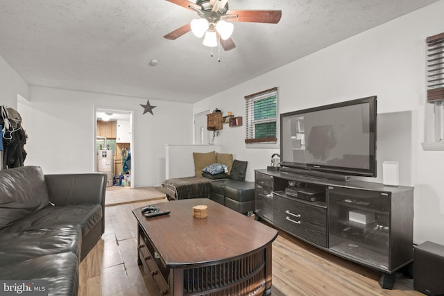 living room with ceiling fan, a textured ceiling, gas water heater, and light hardwood / wood-style floors