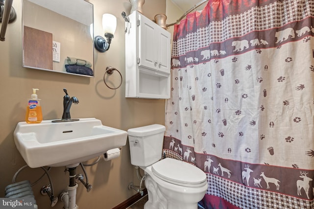 bathroom featuring curtained shower, sink, and toilet