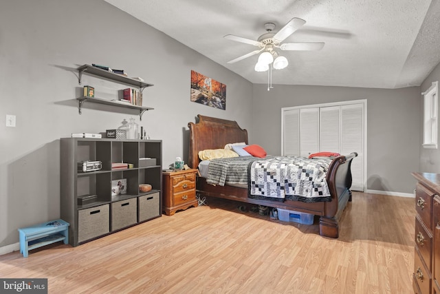 bedroom featuring ceiling fan, a closet, vaulted ceiling, light hardwood / wood-style flooring, and a textured ceiling