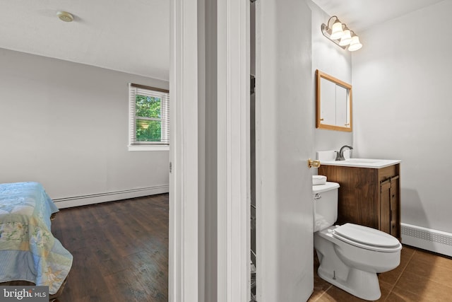 bathroom featuring wood-type flooring, vanity, baseboard heating, and toilet